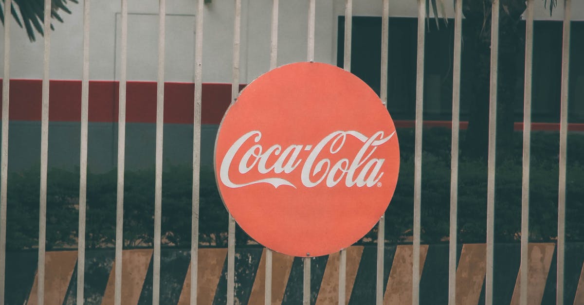 Coca-Cola logo prominently displayed on outdoor fence, urban setting.